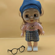 Toy doll wearing a pink shirt with a logo and denim accessories on a beige background